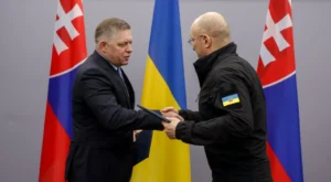 Роберт Фіцо тисне руку українському представнику над документом під прапорами Словаччини та України