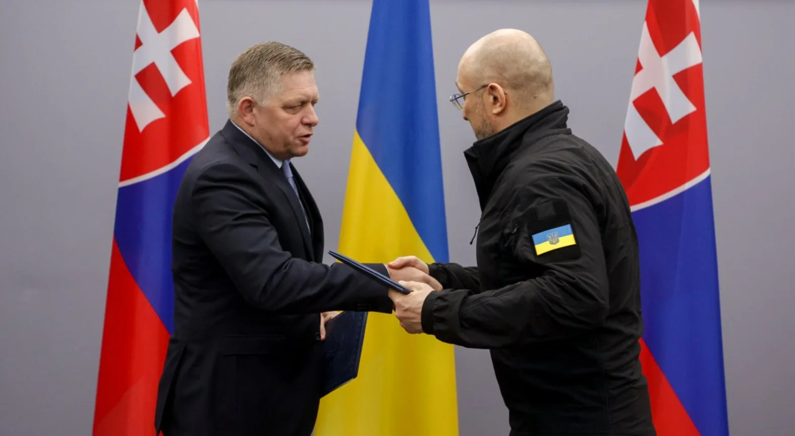 Роберт Фіцо тисне руку українському представнику над документом під прапорами Словаччини та України