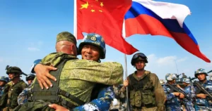 Російські та китайські військові обіймаються під прапорами під час спільних тренувань