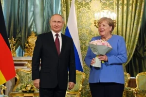 Ангела Меркель з букетом троянд поруч з Путіним під прапорами Німеччини та РФ