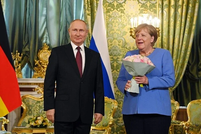 Ангела Меркель з букетом троянд поруч з Путіним під прапорами Німеччини та РФ
