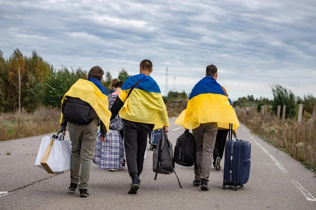 Українці з прапорами та валізами йдуть дорогою за кордон