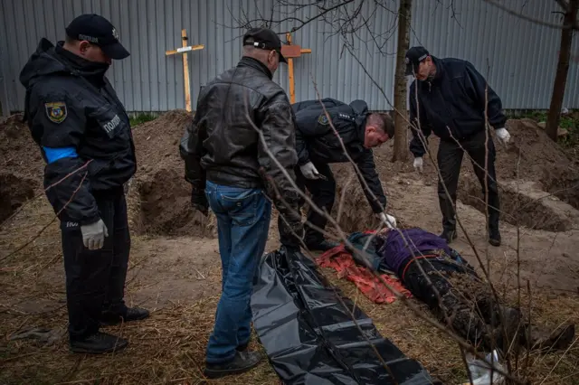 Слідчі оглядають тіло жертви катувань у Бучі під час ексгумації