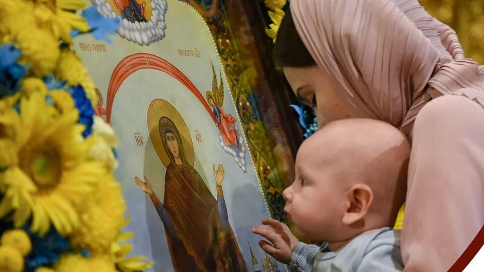 Мать с ребенком почитают икону Богородицы в храме ПЦУ