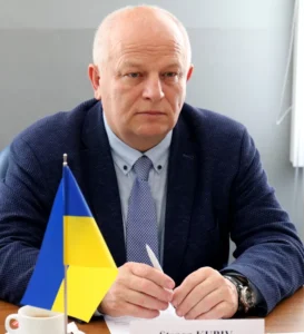 Степан Кубів за столом з прапором України та іменною табличкою