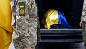 Військові ЗСУ транспортують тіло загиблого захисника під прапором України