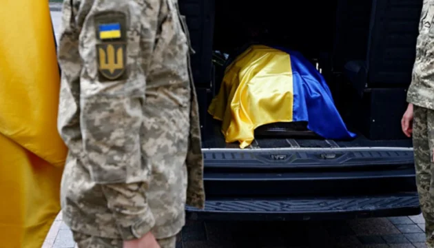 Військові ЗСУ транспортують тіло загиблого захисника під прапором України