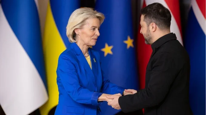 Володимир Зеленський потискає руку Урсулі фон дер Ляєн перед прапорами України та ЄС