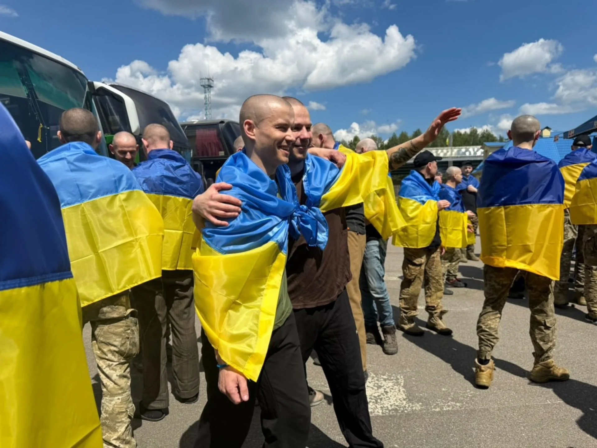 Звільнені з російського полону українці загорнуті в прапори біля автобусів