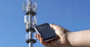 Смартфон у руці перед вежею мобільного звязку Vodafone