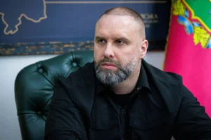 Сергей Корецкий в рабочем кабинете на фоне карты и флага