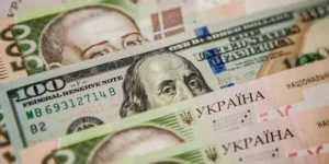 Курс доллара: банкноты 100 USD и 100 гривен на фоне валютного рынка