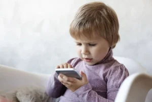 Ребёнок трёх лет держит смартфон, иллюстрируя ранний доступ к гаджетам