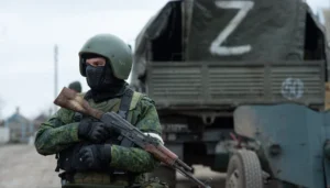Російський військовий зі знаком Z на тлі вантажівки під час агресії РФ проти України