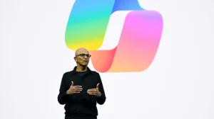 Сатья Наделла на фоне логотипа Microsoft предупреждает о рисках ИИ-промптов