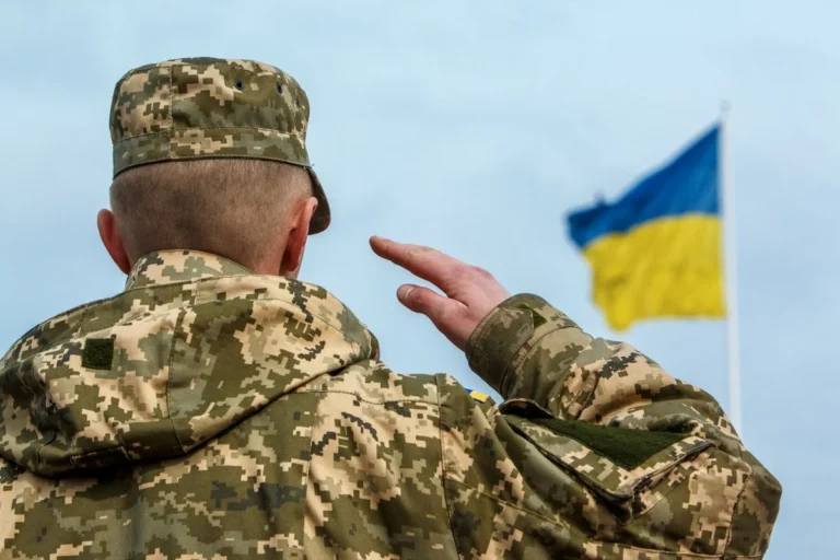 Военнослужащий ВСУ салютует флагу Украины во время военного положения