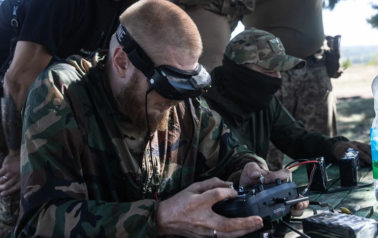 Військовий у камуфляжі з FPV-окулярами керує дроном на полігоні