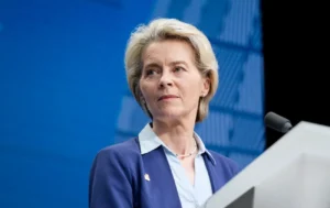 Урсула фон дер Ляєн виступає за трибуною на тлі синього екрану ЄС