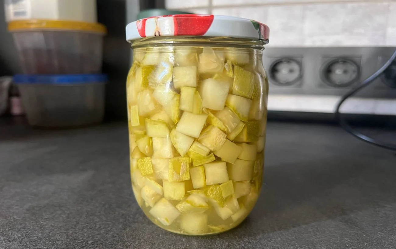 Скляна банка з кубиками кабачків у сиропі на кухонній стільниці