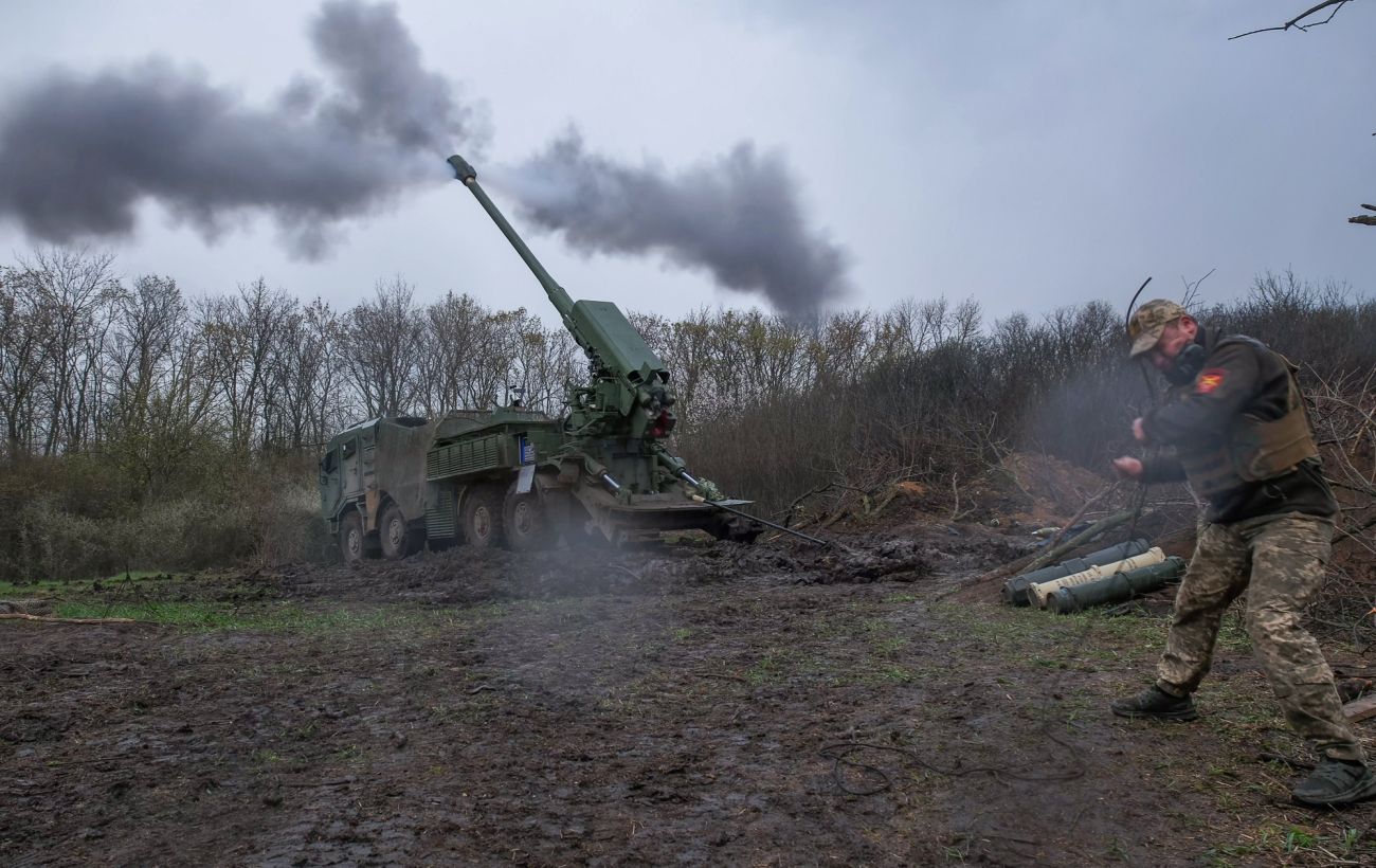 Український артилерист біля стріляючої самохідної 155-мм гаубиці в багнюці